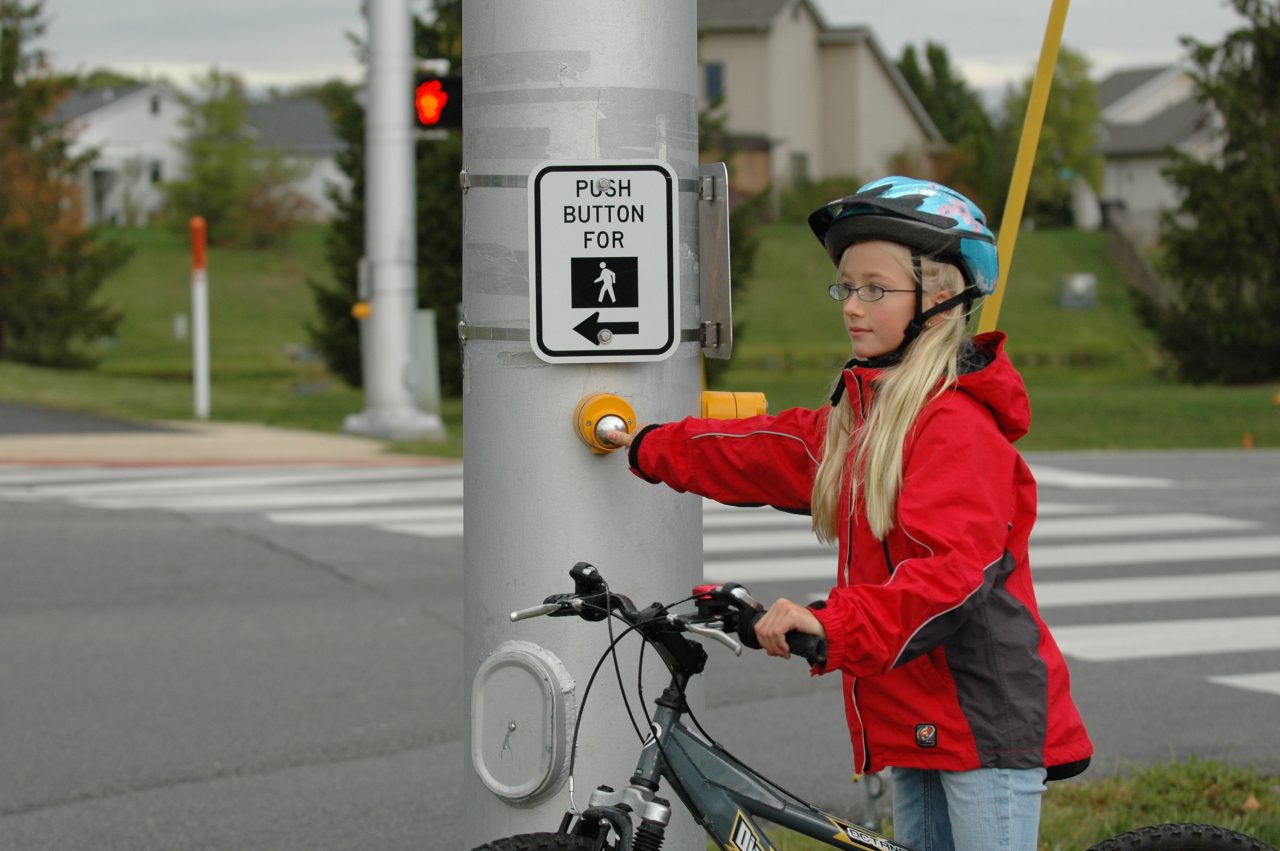 Child using cross-walk button for signal.